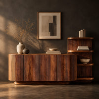 Corner detail of long fluted sideboard with curved ends and an open shelf tower at one end beside wood, brass and linen samples