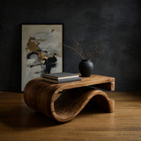 Folded S ribbon coffee table in a dark studio against a charcoal wall