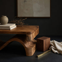 Corner detail of folded S ribbon coffee table beside wood, brass and linen samples