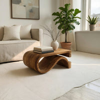 Folded S ribbon coffee table in a sunlit room with large windows and plants