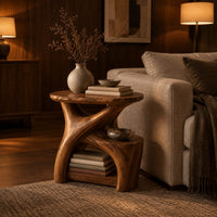 Forked branch side table with an oval top and open lower shelf in an evening living room with walnut wall paneling