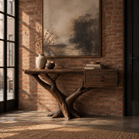 Console table on a forked tree base with two drawers at one end in an industrial loft entryway with exposed brick
