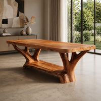 Corner detail of rectangular dining table on two forked trunk legs joined by a low beam beside wood, brass and linen samples