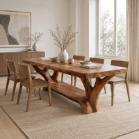 Rectangular dining table on two forked trunk legs joined by a low beam in a Scandinavian dining room with white walls