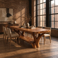 Rectangular dining table on two forked trunk legs joined by a low beam in an industrial loft dining room with exposed brick
