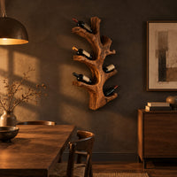 Wine rack shaped like a branching tree trunk with forked arms for bottles in a dark dining room at golden hour