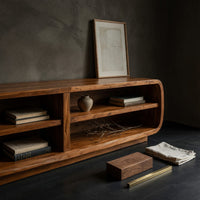 Corner detail of rounded TV cabinet with four open cubbies beside wood, brass and linen samples