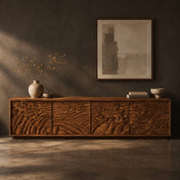 Corner detail of long low tv stand with four doors carved in deep rippling wave relief beside wood, brass and linen samples