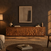 Long low tv stand with four doors carved in deep rippling wave relief in a dark living room at golden hour