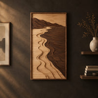 Framed wall art showing a carved river landscape in light and dark wood on a dark charcoal plaster wall