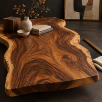 Corner detail of long wood tabletop with uneven natural edges and bold swirling grain beside wood, brass and linen samples