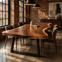 Long wood tabletop with uneven natural edges and bold swirling grain in an industrial loft dining room with exposed brick