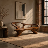 Long freeform bench with oval cutouts along the back and flared legs in an industrial loft entryway with exposed brick