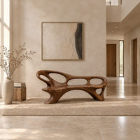 Long freeform bench with oval cutouts along the back and flared legs in a bright open plan entryway