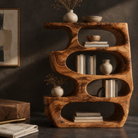Corner detail of freeform bookshelf with four stacked oval openings and a thick wavy outline beside wood, brass and linen samples