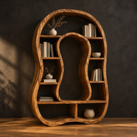 Freeform bookshelf with a keyhole shaped center opening and uneven shelves in a dark studio against a charcoal plaster wall