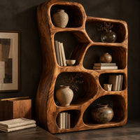 Corner detail of freeform wooden bookshelf with irregular open cubbies of different sizes beside wood, brass and linen samples