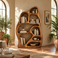 Freeform bookshelf with irregular openings in a sculpted organic frame in a bright living room with arched windows and plants