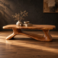 Freeform wooden coffee table with a sculpted branching base in a dark studio against a charcoal plaster wall