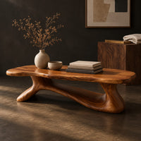 Corner detail of freeform wooden coffee table with a sculpted branching base beside wood, brass and linen samples
