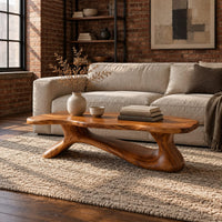 Freeform wooden coffee table with a sculpted branching base in an industrial loft living room with exposed brick