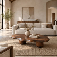 Freeform coffee table with a wavy edged top and two thick cylinder legs in a bright open plan living room