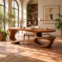 Freeform oval desk with an open loop base and a low shelf in a bright home office with arched windows and plants