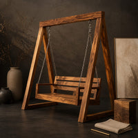 Corner detail of freestanding a frame swing with a cushioned bench seat on chains beside wood, brass and linen samples