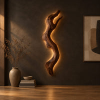 Tall wall sconce shaped like a gnarled twisting branch with a glowing halo in a dark studio against a charcoal plaster wall