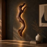 Tall wall sconce shaped like a gnarled twisting branch with a glowing halo, three-quarter view showing the grain
