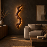 Tall wall sconce shaped like a gnarled twisting branch with a glowing halo in a dark living room at golden hour
