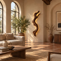 Tall wall sconce shaped like a gnarled twisting branch with a glowing halo in a bright living room with arched windows and plants