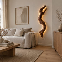 Tall wall sconce shaped like a gnarled twisting branch with a glowing halo in a Scandinavian living room with white walls