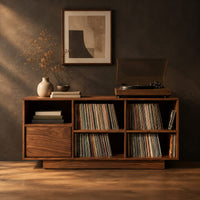 Low cabinet with a grid of open cubbies and a slim plinth base in a dark studio against a charcoal plaster wall