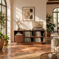 Low cabinet with a grid of open cubbies and a slim plinth base in a bright living room with arched windows and plants