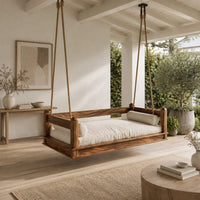 Hanging daybed swing with low wood rails and a thick seat pad in a Scandinavian porch with white walls