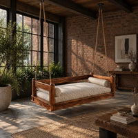 Hanging daybed swing with low wood rails and a thick seat pad in an industrial loft porch with exposed brick