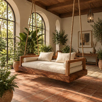 Hanging daybed swing with a thick wood base and low frame sides in a bright porch with arched windows and plants