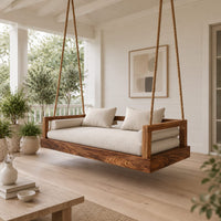 Hanging daybed swing with a thick wood base and low frame sides in a Scandinavian porch with white walls