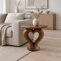 Round side table on a sculpted pedestal with a heart shaped opening in a Scandinavian living room with white walls