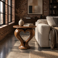 Round side table on a sculpted pedestal with a heart shaped opening in an industrial loft living room with exposed brick
