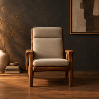 High back lounge chair with cushioned seat and sweeping wood arms in a dark studio against a charcoal plaster wall