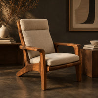Corner detail of high back lounge chair with cushioned seat and sweeping wood arms beside wood, brass and linen samples