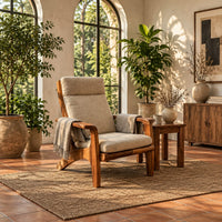 High back lounge chair with cushioned seat and sweeping wood arms in a bright living room with arched windows and plants