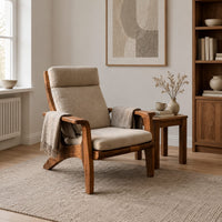 High back lounge chair with cushioned seat and sweeping wood arms in a Scandinavian living room with white walls