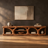 Long low media console with hollowed arch openings and open shelf bays in a dark studio against a charcoal plaster wall