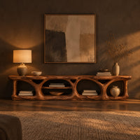 Long low media console with hollowed arch openings and open shelf bays in a dark living room at golden hour