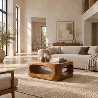 Chunky block coffee table with large oval tunnel openings through its sides in a bright open plan living room