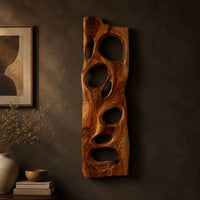 Wooden wall art panel with irregular oval cutouts on a dark charcoal plaster wall