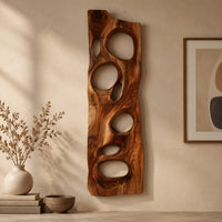 Detail of wooden wall art panel with irregular oval cutouts beside wood, brass and linen samples